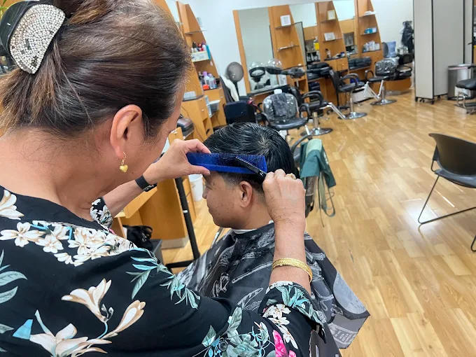 A stylist at Christina's sections a client's hair with a comb before cutting it.