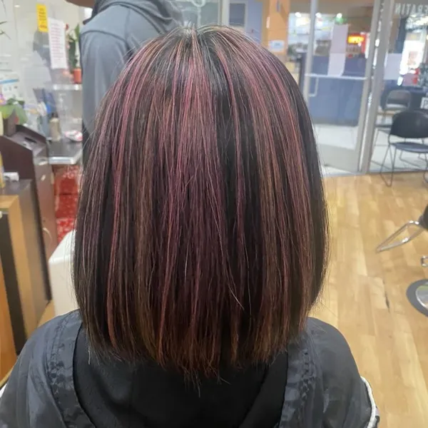 A sleek bob with dark hair and rich plum-pink highlights.