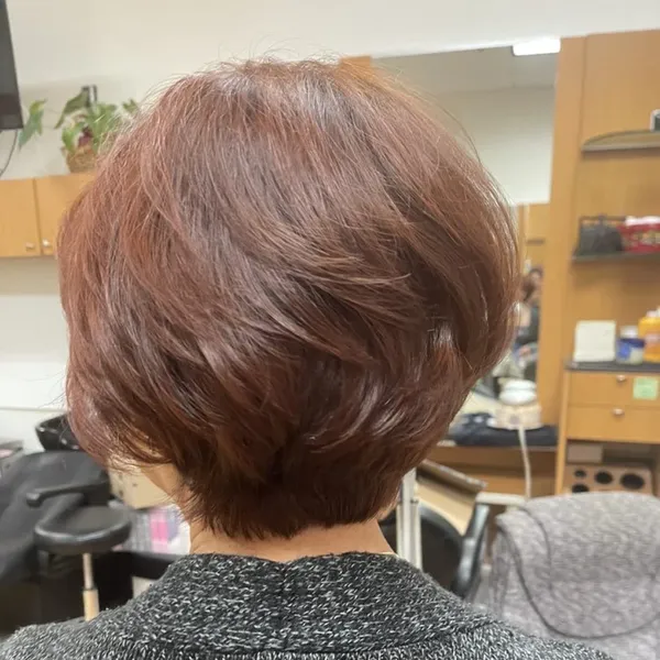 A short, layered cut colored a warm auburn red.