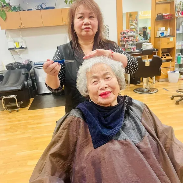 A stylist with a smiling senior client after her cut and curl.
